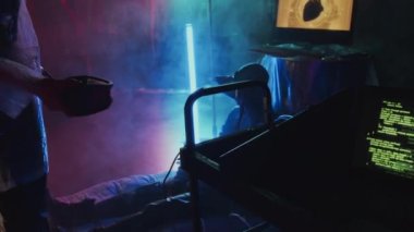 Orta uzunluktaki plastik kaplı Siber punk kızı metaevrenle bağlantılı Afro-Amerikalı adamı kontrol ediyor. Gizlendiği yerde neon ışıkları ve dumanla oturuyor.