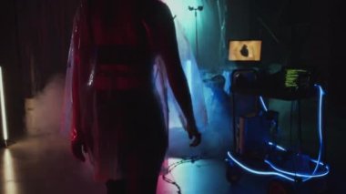 Orta uzunluktaki plastik montlu Siberpunk kız, bilgisayarlı tramvayı neon lambalı ve dumanlı bir şekilde gizliyor.