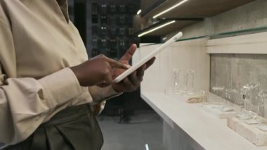 Kadın kuyumcu müdürünün orta bölümü ürünleri sisteme yerleştirmek için aygıt kullanıyor.