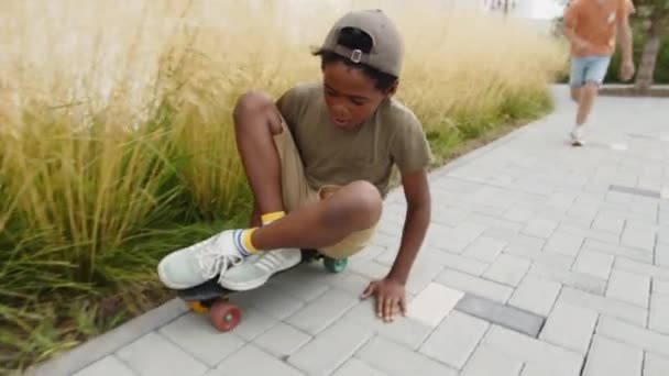 Полный Последующий Снимок Веселого Афроамериканского Летнего Мальчика Сидящего Скейтборде Катающегося — стоковое видео