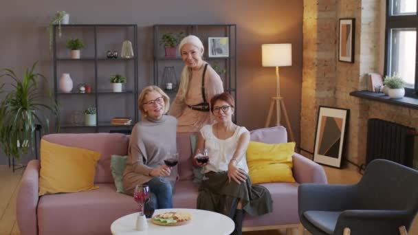 3つの良い見て成熟した女性の肖像画ともに赤ワインの眼鏡をかけたカメラのためにソファで現代のロフトスタイルのリビングルーム — ストック動画