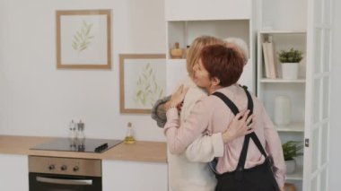 Üç olgun kadın küçük bir akşam yemeği partisi için mutfakta toplanırken birbirlerini kucaklıyorlar.