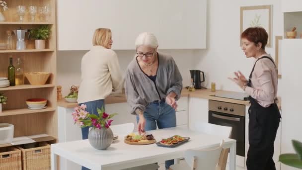 Olgun Kadın Mutfak Masasında Aperatifler Bardaklarda Kırmızı Şarap Servisi Yapıyor — Stok video