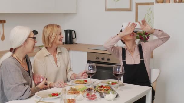 Kulaklıklı Büyülenmiş Yetişkin Bir Kadın Mutfak Masasında Iyi Iki Arkadaşıyla — Stok video