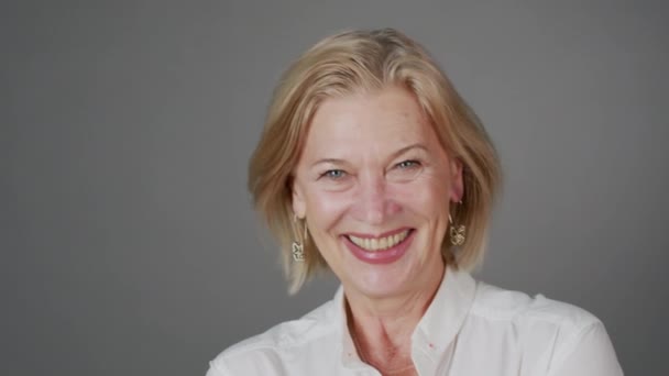 Gri Arka Planda Kameraya Gülümseyen Çekici Beyaz Kadın Portresi — Stok video