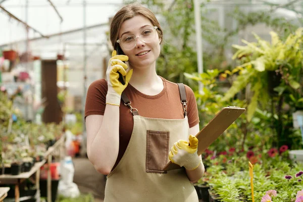 Önlüklü Genç Çiçekçi Elinde Pano Çiçekçide Dururken Cep Telefonuyla Müşteriyle — Stok fotoğraf