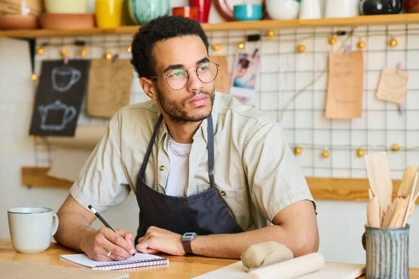 Jonge Pensive Zwarte Man Werkkleding Kijken Opzij Tijdens Het Zitten — Stockfoto