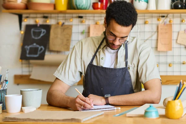 African American Guy Apron Making Notes Notepad While Sitting Table — Stock Photo, Image