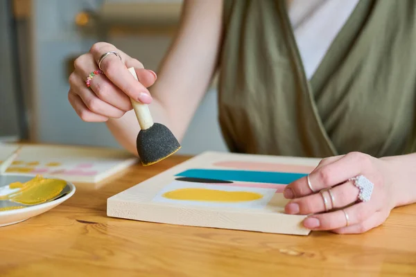 テーブルによる新しい抽象画を描きながら 紙の上にガッシュを塗るためのスポンジを持つ若い創造的な女性の手 — ストック写真