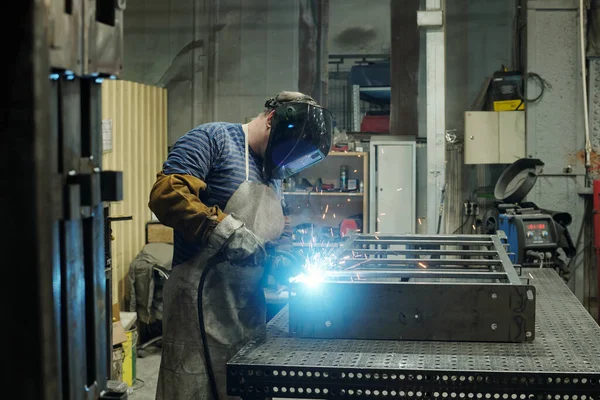 溶接作業を行う一方で 大規模な金属作業台上に曲げ巨大な工業プラントや製造業の男性労働者の側面図 — ストック写真