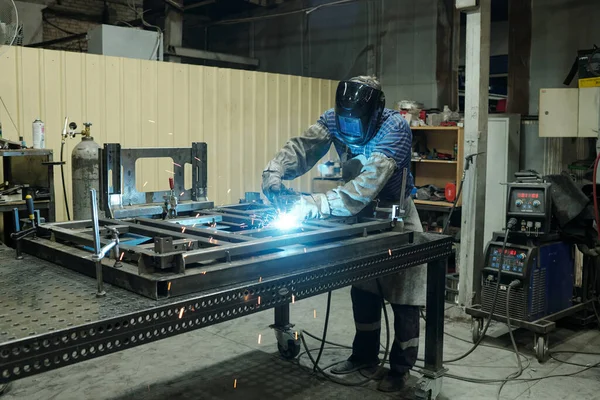 Ung Manlig Arbetare Industrianläggning Böjning Över Metalliska Arbetsbänk Och Svetsdelar — Stockfoto