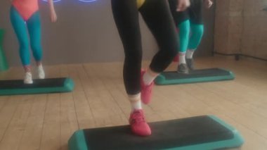 Beyaz kadın fitness eğitmeninden, 80 'lerin aerobik kıyafetleri içindeki erkek ve kadın stüdyoda grup çalışması dersleri alıyor.