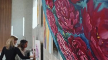 Sanat galerisinde, gün içinde duvardaki çiçek resmine yakın plan, arka plan üzerinde çalışan insanları bulanıklaştırdı