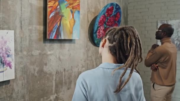 美術館の壁に描かれた絵画のスマートフォンで写真を撮るドレッドロックを持つ白人の少女の背面図 — ストック動画