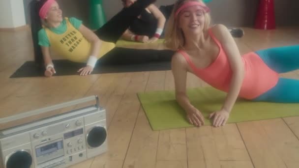 여성들 남성들은 스튜디오에서 운동용 매트에 카메라로 웃으며 녹음기로 자전거를 운동을 — 비디오