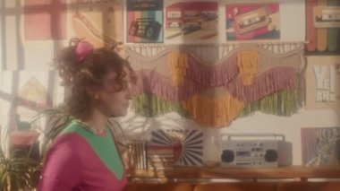 80 'lerin aerobik kıyafetleriyle spor yapan kızıl saçlı beyaz bir kız öğleden sonra oturma odasındaki retro TV' de çalışıyor.