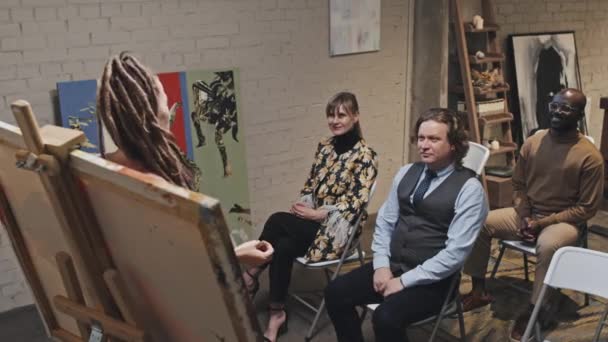 高视角的白人女性艺术家 有着可怕的头发 展示着她的作品 在艺术画廊里演讲 观众坐在椅子上 欢呼着 — 图库视频影像