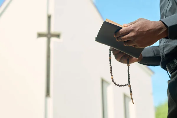 説教中に聖書を読み 説明しながら バラ色のビーズと開かれた福音を持った黒い衣を着た祭司の手 — ストック写真