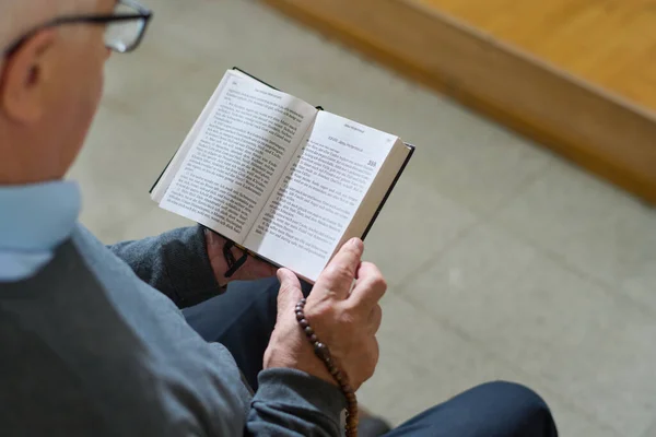 教会で説教中に福音書の一つを読んでいる間に開かれた聖書を保持している犠牲者で成熟した男性のショットの上に — ストック写真