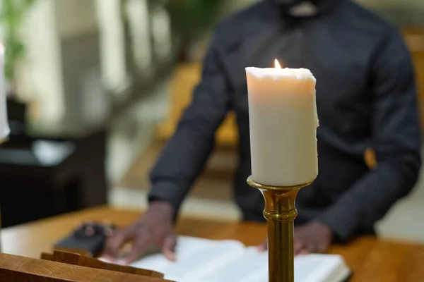 教会の礼拝中に説教壇に立ち説教をしながら 聖書からの聖句を読む祭司の背景に白いロウソクを燃やす — ストック写真