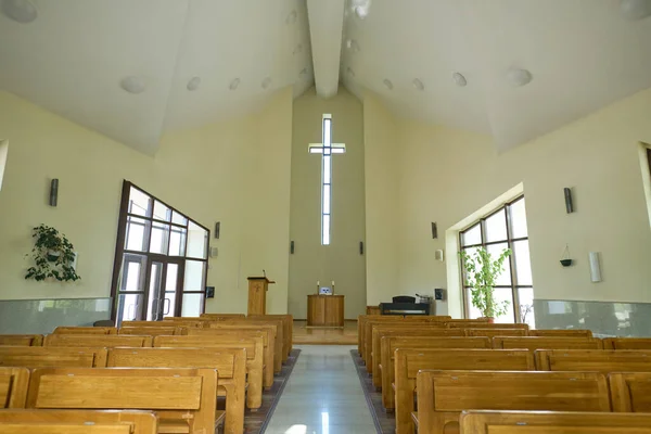 教会の礼拝のための空のホール教区のための木製のベンチの2行と牧師の説教壇の上の十字架の間の通路 — ストック写真