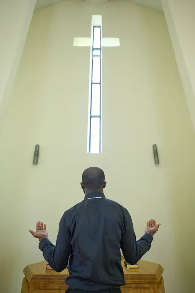 Siyah Kıyafetli Genç Afrikalı Papazın Mihrapta Kürsüde Çarmıhın Önünde Dua — Stok fotoğraf