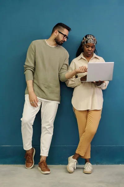 两名年轻的跨文化同事身着便服 在准备演讲时讨论了黑人妇女在笔记本电脑屏幕上的在线数据 — 图库照片