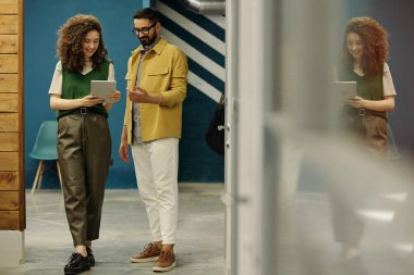 Güzel bir iş kadını tarafından tutulan dijital tablet ekranına bakarken çevrimiçi verileri tartışan iki başarılı simsar veya analist