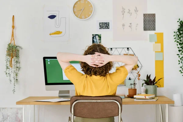 年轻的自由职业设计师坐在电脑显示器前休息几分钟 双手放在脑后的后视镜 — 图库照片
