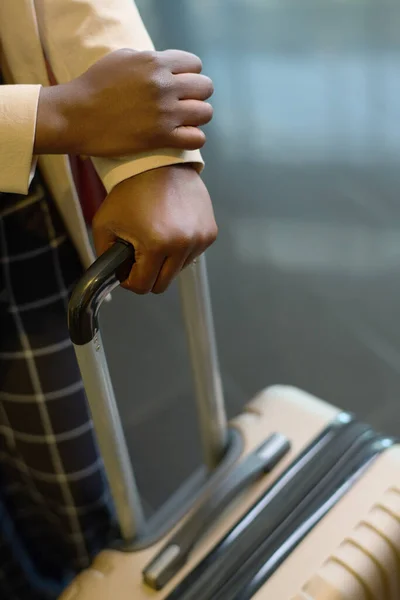 ホテルのラウンジに立ち ベルボーイを待っている間に荷物付きのスーツケースのハンドルで保持する若いエレガントな黒人女性の手 — ストック写真