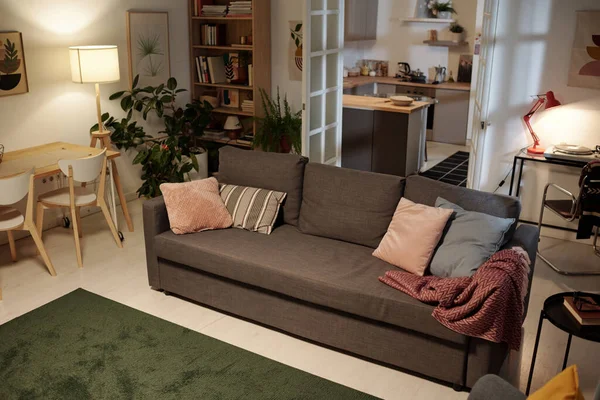 他の家具に囲まれた中心部にいくつかのクッションと長い柔らかい快適なソファ付きの広々としたリビングルームのインテリア — ストック写真