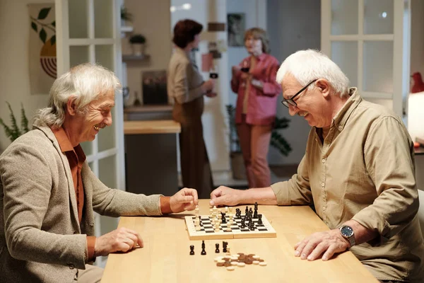 黒と白のチェッカーでチェスボードを見てカジュアルウェアで二人の陽気な引退した男性と数字前にゲームをプレイ開始 — ストック写真