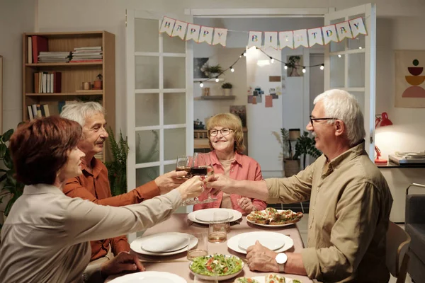 一群兴高采烈的老年人聚集在餐桌旁 用酒杯庆祝生日 享用自制食品 — 图库照片