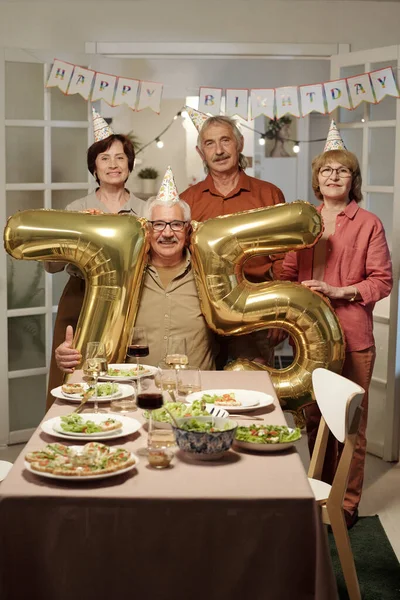 Glückliche Senioren Geburtstagsmützen Stehen Bei Einem Älteren Mann Mit Aufblasbaren — Stockfoto