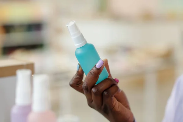 年轻的非洲裔美国女孩手拿着装有蓝色液体的瓶子 快速烘干指甲油 同时选择新的化妆品 — 图库照片