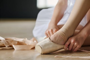 Sınıfın veya stüdyonun zemininde otururken tekrarlamadan önce noktalı ayakkabı giyen balerin elleri yakın plan.