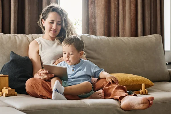 可爱的小男孩在和祖父母视频聊天时 看着妈妈拿着的平板电脑屏幕上的人 — 图库照片