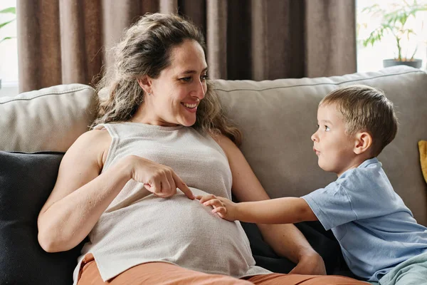 可爱的小男孩和他怀孕的母亲一边玩耍一边指着自己的肚子 谈论着自己的新生活 — 图库照片