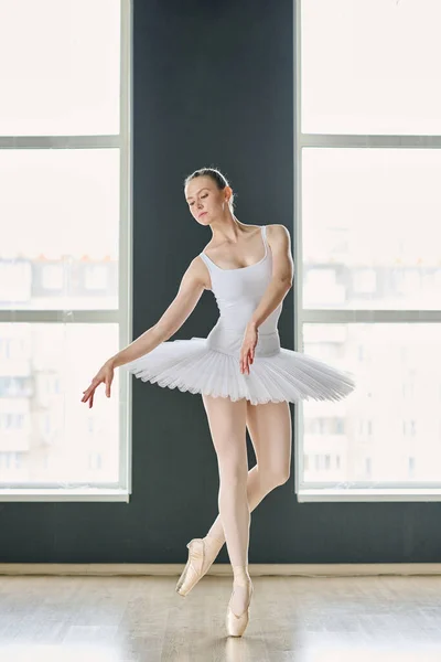 年轻优雅的芭蕾舞蹈家 身穿白色短裙和紧身衣 脚尖站立 一条腿屈膝弯向一边 — 图库照片