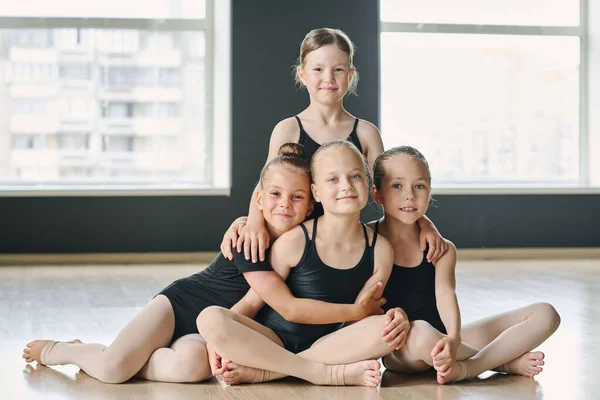 スタジオやダンスホールの床に座って繰り返しとカメラを見て黒の足で幸せな若い女の子のグループ — ストック写真