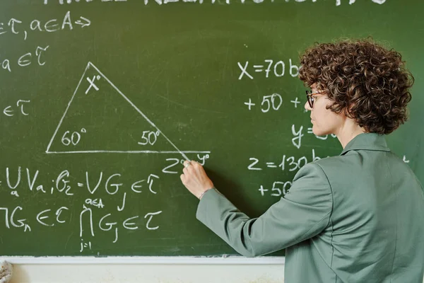大专院校年轻而严肃的教师一边在黑板上钻三角形一边向观众解释定理 — 图库照片