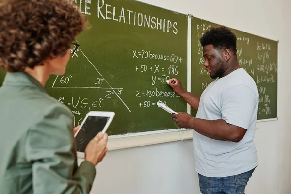 非裔美国学生在黑板上写下代数方程或公式 并在课堂上向老师解释 — 图库照片