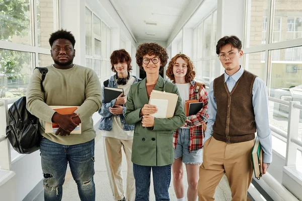 幸せな若い先生と陽気な多文化10代の学生です学生の廊下に立つ大学や大学 — ストック写真