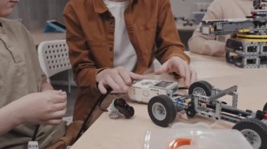 Kafkas ergen öğrenci okulda ders sırasında arkadaşıyla robotik araba modeli üzerinde çalışıyor programlama hakkında konuşuyor.