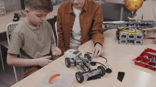 Okulda Robotik Oyuncak Araba Modeli Üzerinde Çalışan Iki Beyaz Gencin — Stok video