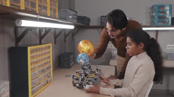 Young Middle Eastern Teacher Helping Black Student Robotic Solar System — Stock Video