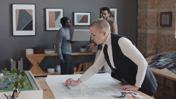 白种人妇女白天剃光头在现代办公室工作蓝图的中等侧视图 — 图库视频影像