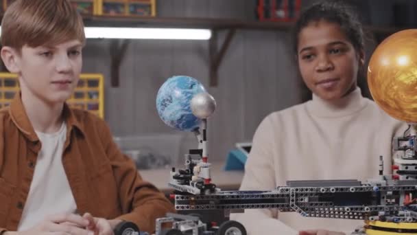 Fröhliches Schwarzes Mädchen Und Kaukasischer Junge Arbeiten Zusammen Einem Roboter — Stockvideo