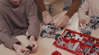 Okulda tanınmayan öğretmen ve öğrencilerinin robotik araba modelleri yapmasının yüksek açılı görüntüsü