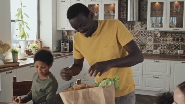 Средний Молодой Афроамериканец Отец Двух Мальчиков Приносящих Продукты Вынимающих Покупки — стоковое видео